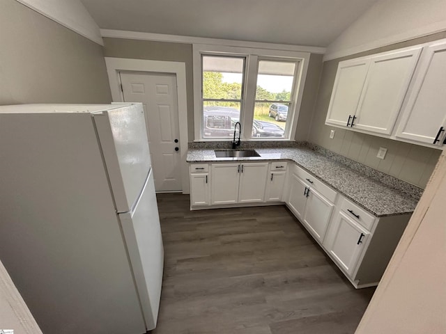 kitchen featuring lofted ceiling, white fridge, sink, and white cabinets