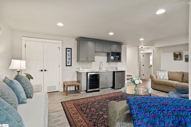 living room featuring beverage cooler, indoor wet bar, and light wood-type flooring