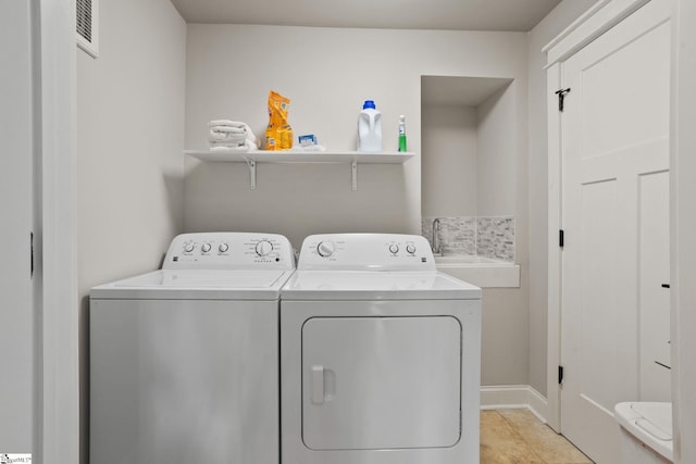 laundry area with washer and clothes dryer, sink, and light tile patterned floors