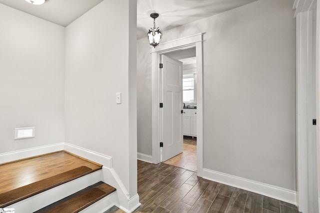 hallway with an inviting chandelier and dark hardwood / wood-style flooring