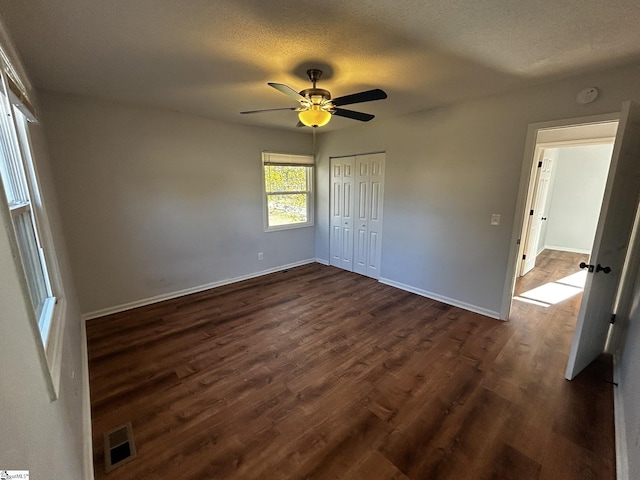 unfurnished bedroom with ceiling fan, dark hardwood / wood-style flooring, a closet, and a textured ceiling