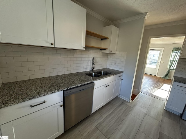 kitchen featuring stainless steel dishwasher, dark stone counters, sink, and white cabinets