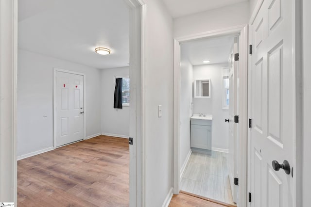 hallway with sink and light hardwood / wood-style floors