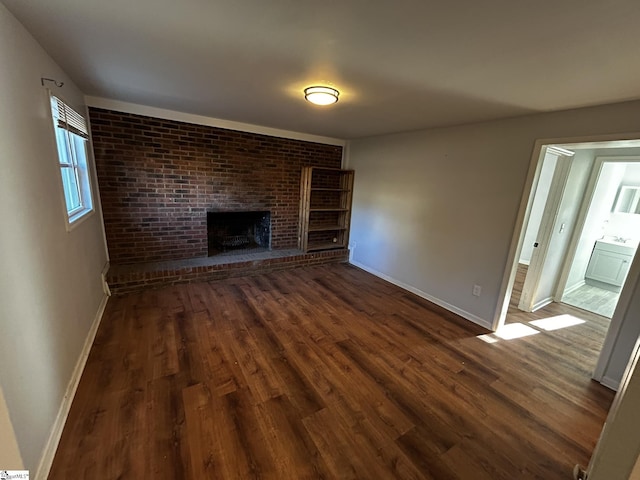 unfurnished living room featuring dark hardwood / wood-style flooring and a brick fireplace