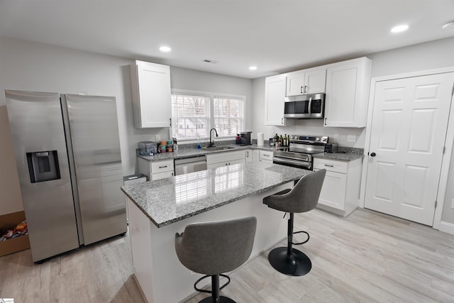 kitchen featuring sink, a kitchen breakfast bar, a kitchen island, stainless steel appliances, and white cabinets