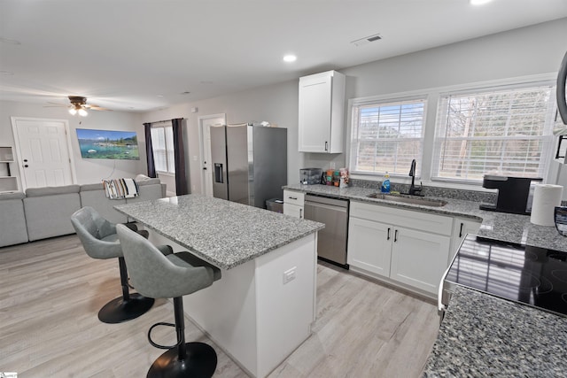 kitchen featuring stainless steel appliances, white cabinetry, light stone countertops, and sink