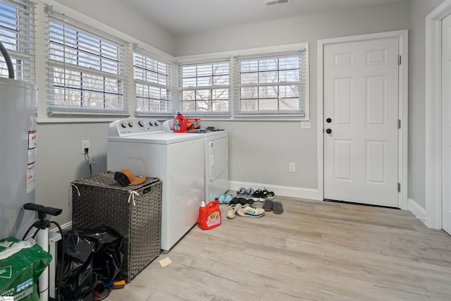 laundry room with water heater, separate washer and dryer, plenty of natural light, and light wood-type flooring