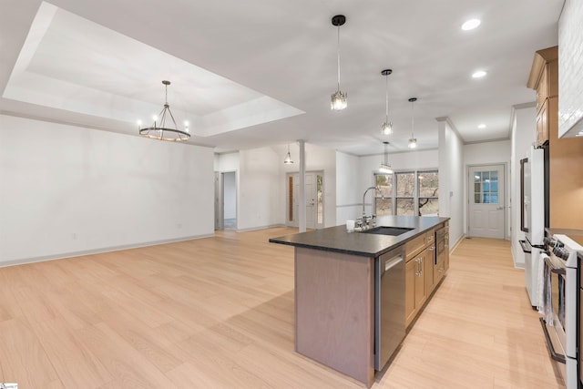 kitchen with sink, decorative light fixtures, light wood-type flooring, appliances with stainless steel finishes, and an island with sink