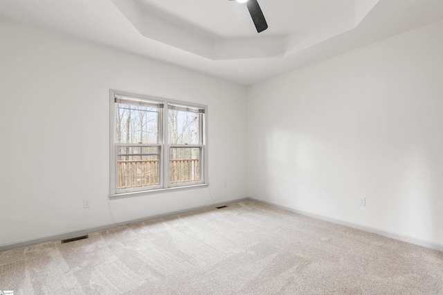 spare room featuring carpet, ceiling fan, and a tray ceiling