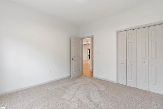 unfurnished bedroom with light colored carpet and a closet