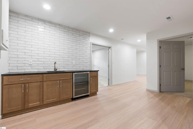 bar featuring wine cooler, light hardwood / wood-style floors, sink, and tasteful backsplash