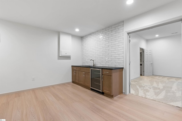 bar with wine cooler, sink, and light hardwood / wood-style flooring