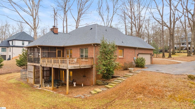 back of house with a garage, a wooden deck, a sunroom, and a yard