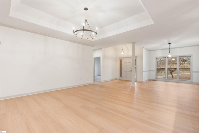 unfurnished living room featuring light hardwood / wood-style flooring, a notable chandelier, and a tray ceiling