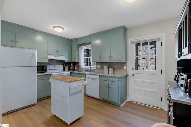 kitchen featuring sink, tasteful backsplash, green cabinetry, light hardwood / wood-style flooring, and white appliances