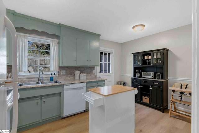 kitchen with sink, backsplash, white dishwasher, and light hardwood / wood-style flooring