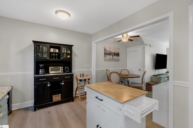 kitchen featuring ceiling fan, light hardwood / wood-style floors, a kitchen island, and white cabinets