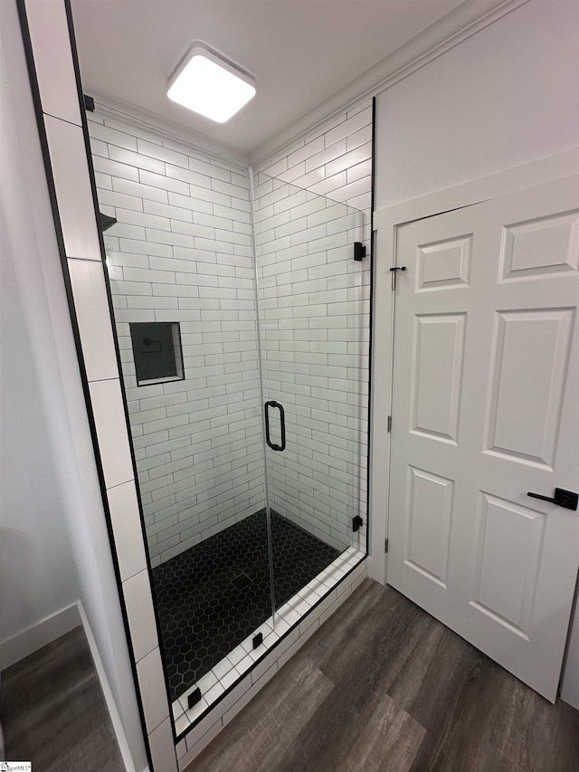 bathroom with hardwood / wood-style floors and a shower with shower door