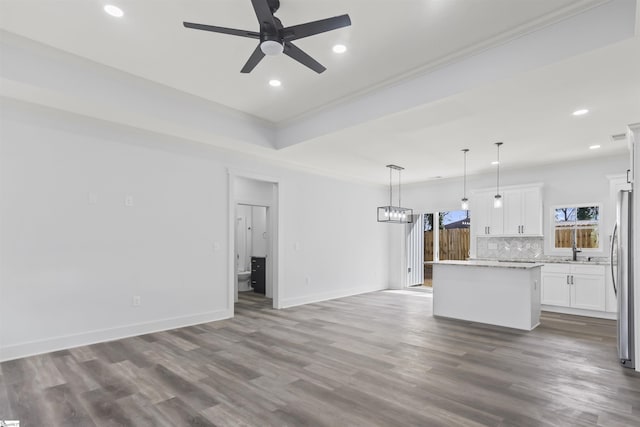 kitchen with white cabinetry, hanging light fixtures, hardwood / wood-style floors, a center island, and decorative backsplash