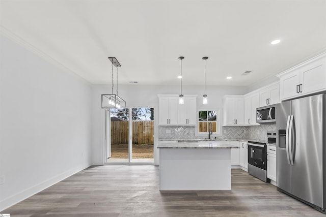 kitchen with appliances with stainless steel finishes, white cabinets, and decorative light fixtures