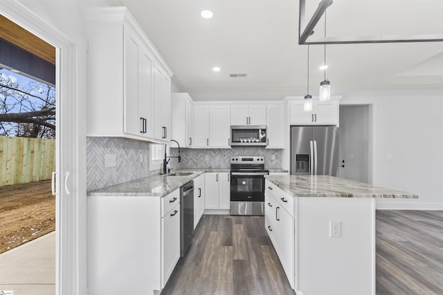 kitchen featuring a kitchen island, decorative light fixtures, white cabinetry, sink, and stainless steel appliances