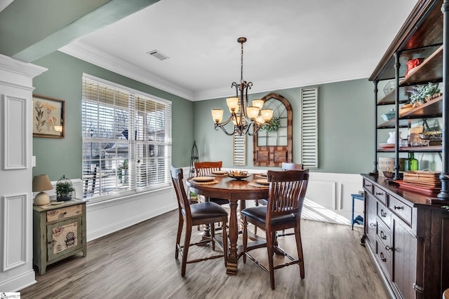 dining area with ornamental molding, a chandelier, and hardwood / wood-style floors