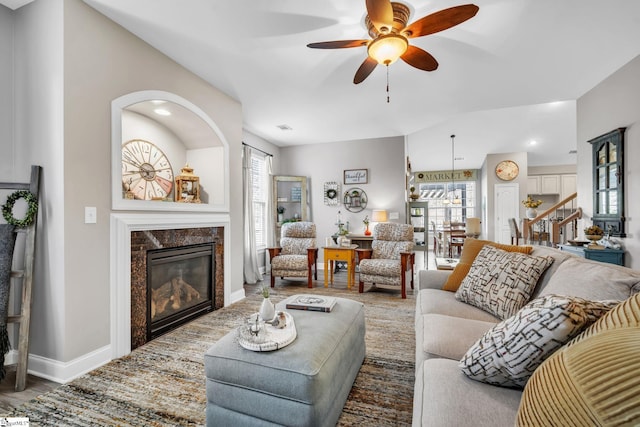 living room with hardwood / wood-style flooring, ceiling fan, and a high end fireplace