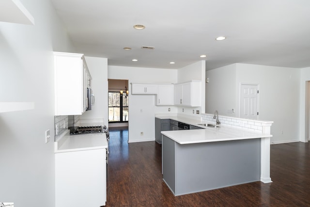 kitchen featuring sink, dark hardwood / wood-style floors, white cabinets, decorative backsplash, and kitchen peninsula