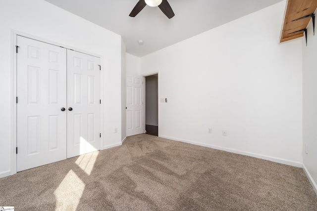 unfurnished bedroom featuring lofted ceiling, a closet, ceiling fan, and carpet