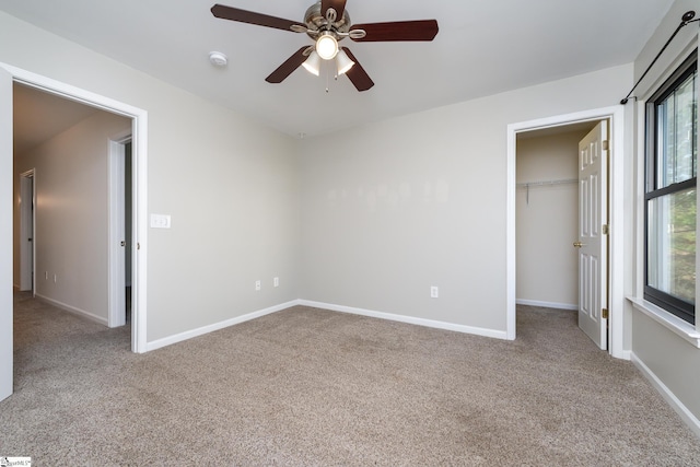 unfurnished bedroom featuring ceiling fan, a spacious closet, carpet floors, and a closet