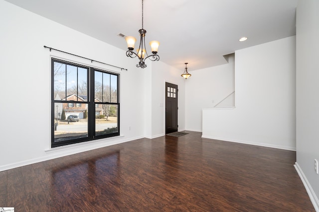 unfurnished room featuring dark wood-type flooring and a notable chandelier