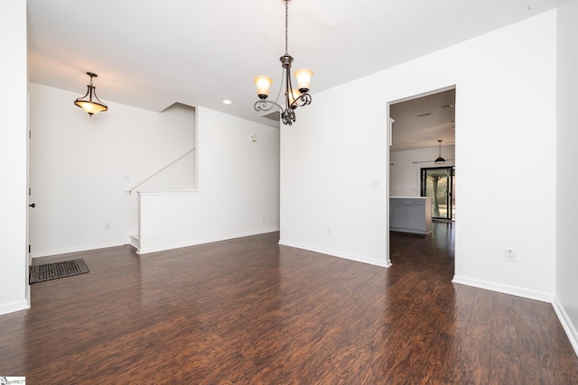 unfurnished room with a notable chandelier and dark hardwood / wood-style floors