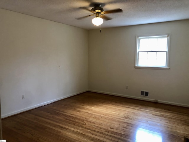 empty room featuring ceiling fan, wood-type flooring, and a textured ceiling