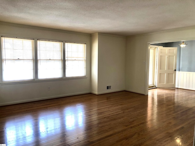 empty room with ornamental molding, dark wood-type flooring, and a textured ceiling