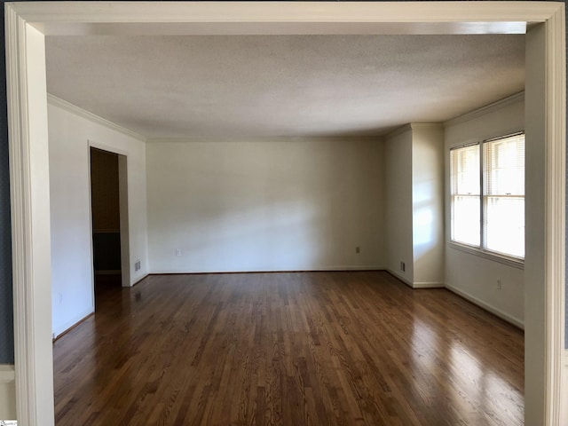 empty room with dark wood-type flooring, crown molding, and a textured ceiling