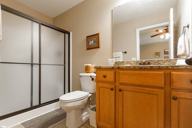 bathroom featuring tile patterned floors, toilet, vanity, a shower with door, and ceiling fan