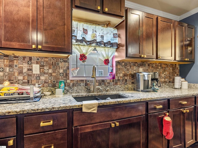 kitchen featuring light stone counters, crown molding, sink, and tasteful backsplash