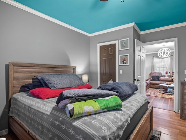 bedroom with a notable chandelier, crown molding, and wood-type flooring