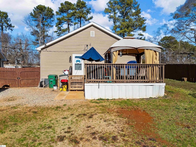 rear view of property featuring a gazebo, a yard, and a deck