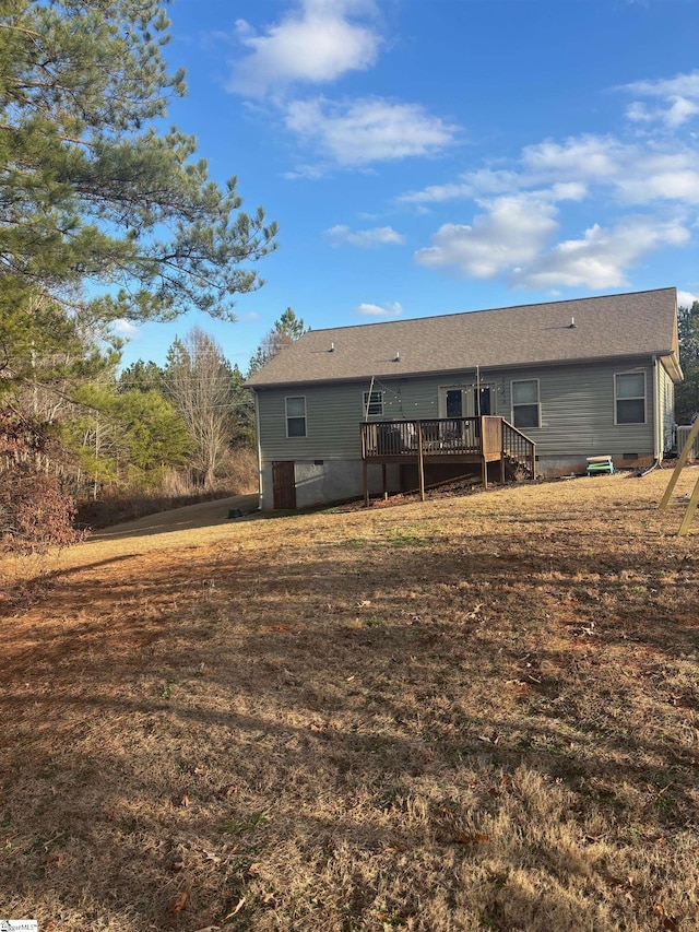 rear view of property with a wooden deck and a yard