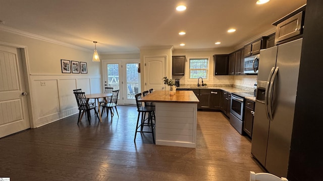 kitchen featuring butcher block counters, sink, appliances with stainless steel finishes, a kitchen island, and pendant lighting