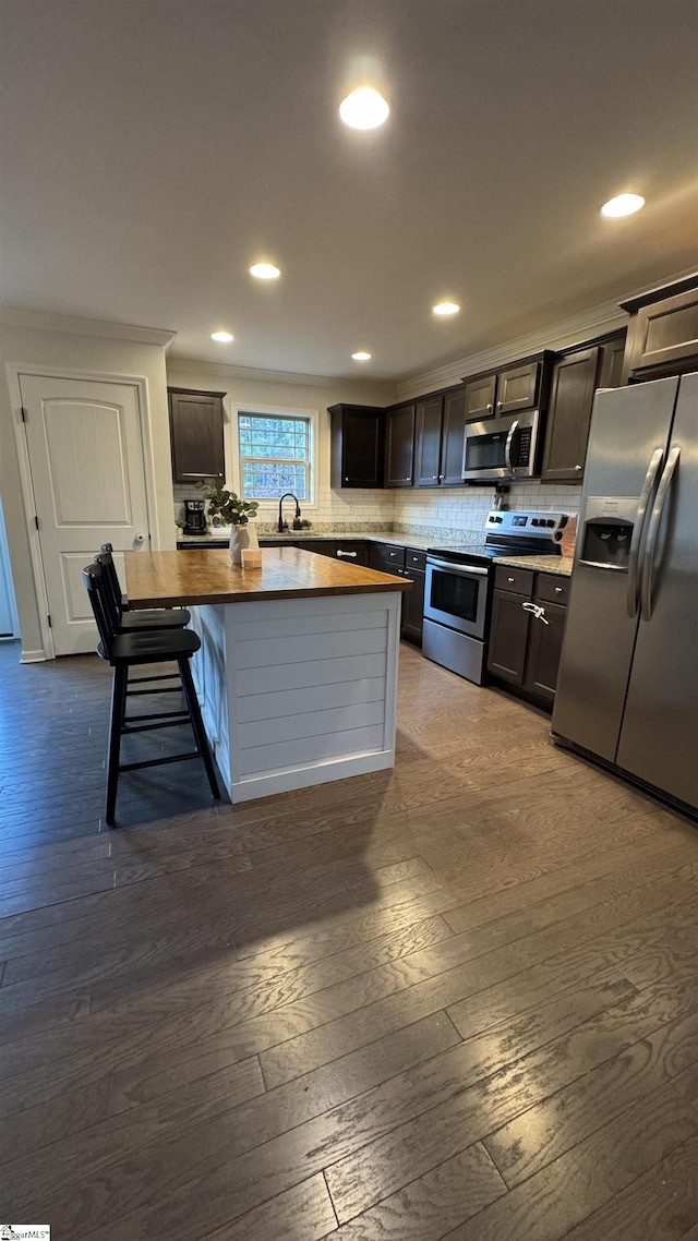 kitchen featuring appliances with stainless steel finishes, wood counters, sink, dark hardwood / wood-style flooring, and decorative backsplash