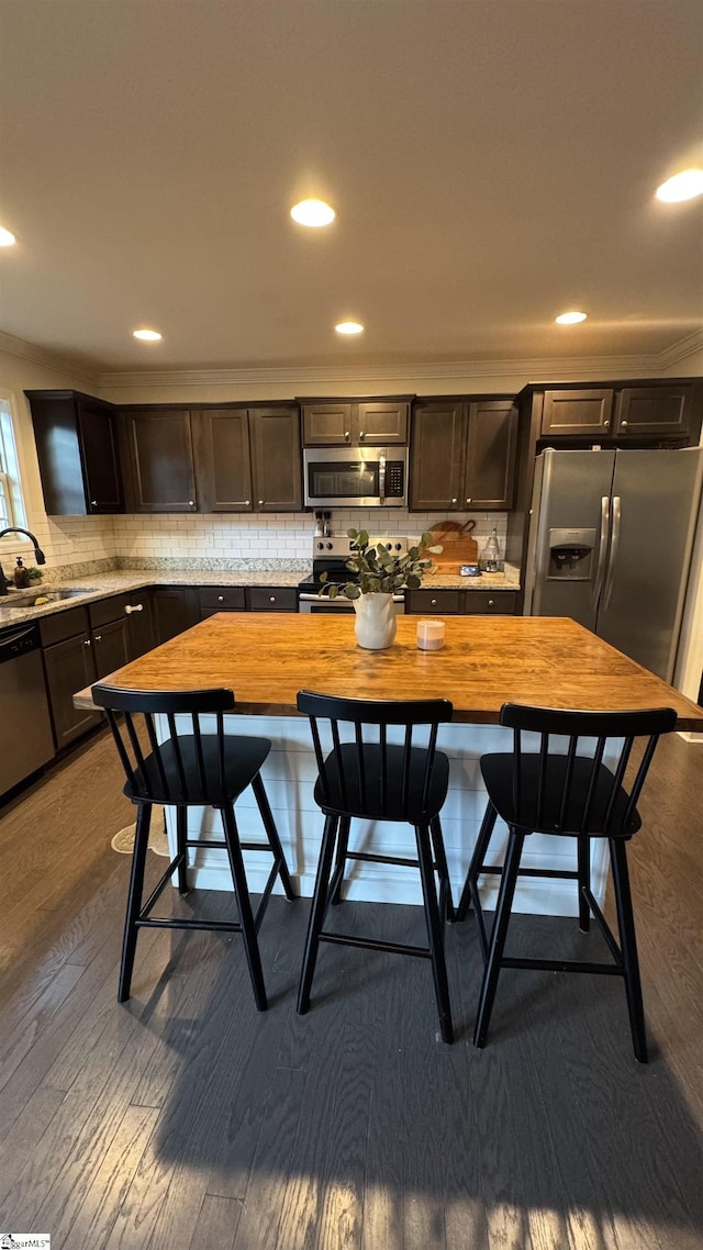 kitchen with sink, appliances with stainless steel finishes, hardwood / wood-style floors, wood counters, and decorative backsplash