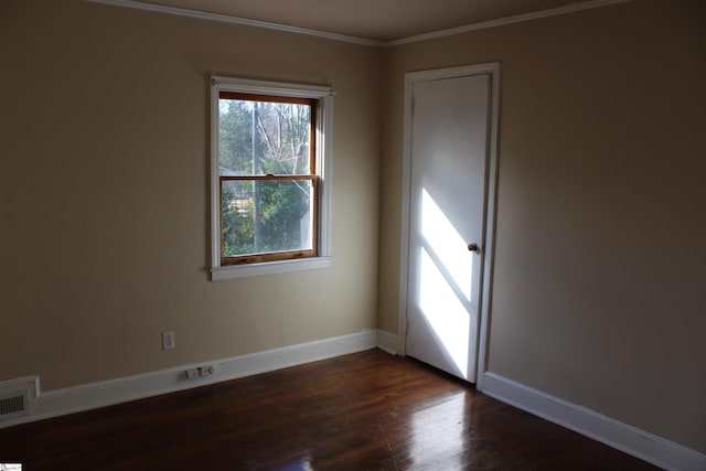 empty room featuring dark hardwood / wood-style flooring and crown molding