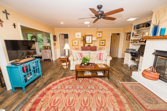 living room with ornamental molding, dark wood-type flooring, ceiling fan, and a fireplace