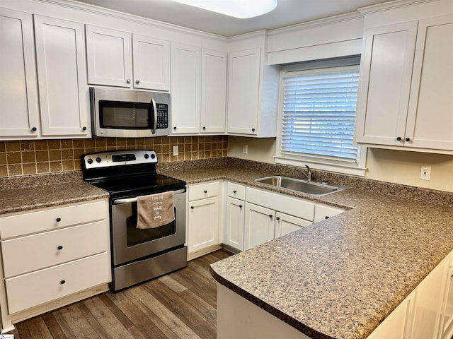 kitchen with appliances with stainless steel finishes, white cabinetry, sink, dark hardwood / wood-style flooring, and decorative backsplash