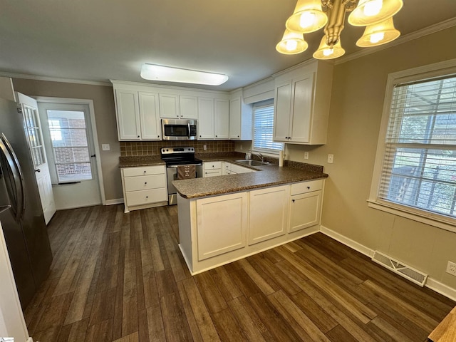 kitchen featuring sink, stainless steel appliances, white cabinets, decorative light fixtures, and kitchen peninsula