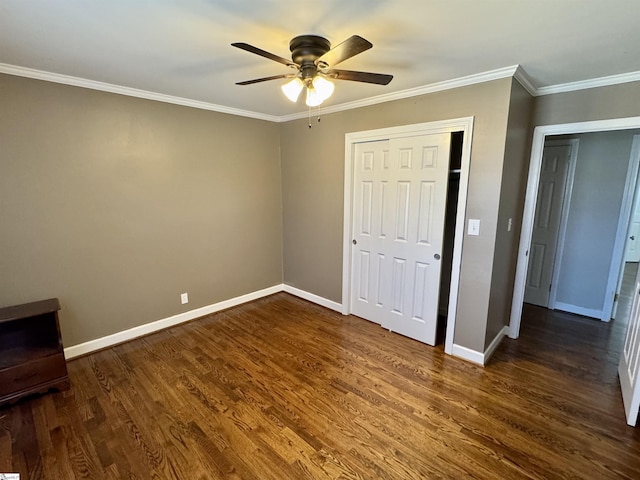 unfurnished bedroom with dark wood-type flooring, ceiling fan, crown molding, and a closet