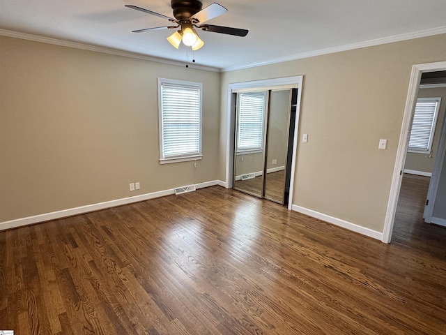 unfurnished bedroom with ornamental molding, ceiling fan, dark hardwood / wood-style flooring, and a closet