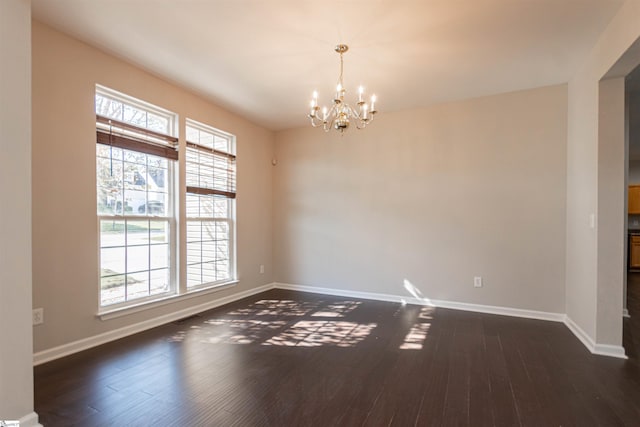 empty room with dark hardwood / wood-style floors and a chandelier